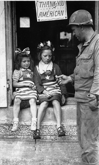 A GI's giving candies to two French girls in Normandy (1944)
