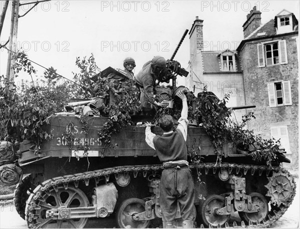 A French civilian giving a glass of wine to a US tank crew