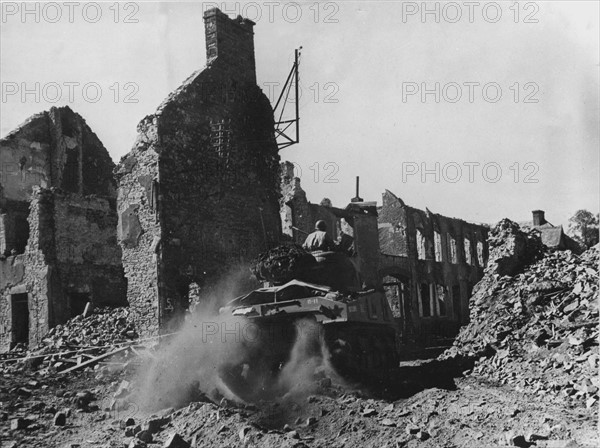 Un char Sherman M-4 américain traverse Périers dévasté, en direction de Coutances