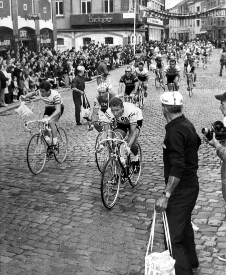 Der Franzose Jacques Anquetil (r.) rollt am 23.06.1966 auf der zweiten Etappe der Tour de France im belgischen Louviere bei der Verpflegungskontrolle an einem Betreuer mit Beutel vorbei. Der aus Rouen stammende Rennfahrer feierte bei der Tour de France insgesamt fünf Gesamtsiege (1957, 1961, 1962, 1963 und 1964). In diesem Jahr muss er wegen einer Erkältung frühzeitig aussteigen.