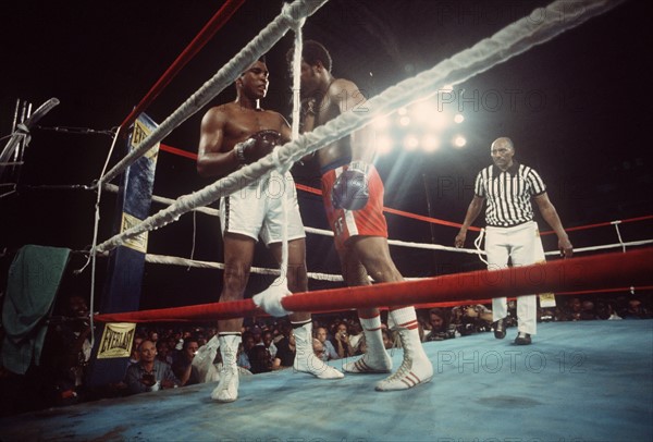 Die US-Schwergewichtsboxer Muhammad Ali (l) und George Foreman (M) kämpfen am 30.101974 in Kinshasa (Zaire) um den Weltmeistertitel. Der Kampf unter Leitung von Ringrichter Dack Clayton (r) gestaltet sich zu einem der sensationellsten der Boxgeschichte. Am Ende schlägt der 32jährige Ali den sieben jahre jüngeren Foreman in der 8. Runde K.o. und feiert ein unerwartetes Comeback als Weltmeister. Der US-Schriftsteller Norman Mailer schreibt über diesen Fight ein Buch, das 1976 unter dem Titel "Der Kampf" erscheint.