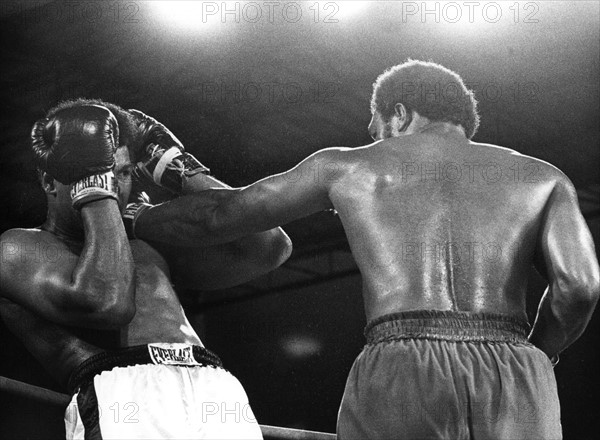 US-Schwergewichtsboxer Muhammad Ali (l) vermeidet in doppelter Deckung einen Kopftreffer seines Kontrahenten und Landsmanns George Foreman. Ali holt sich mit einem sensationellen K.o.-Sieg in der achten Runde gegen den sieben Jahre jüngeren Titelverteidiger am 30.10.1974 in Kinshasa (Zaire) den WM-Titel zurück. Damit ist der 32jährige der zweite Boxer, der den WM-Titel im Schwergewicht zurückerobert.