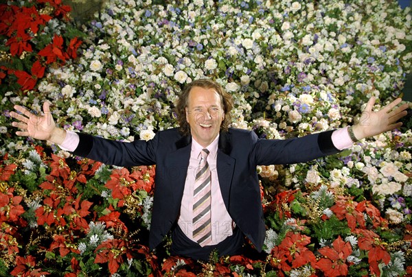 (dpa) - Dutch star violinist Andre Rieu smiles while standing in a sea of artificial flowers in Maastricht, the Netherlands, 02 November 2005. The stage decoration has been placed ready for being packed at the warehouse next to his studio in Masstricht. The 56-year-old musician is about to start the first part of his tour through Canada and the USA, where he will perform at 13 mayor cities. The complete equipment of his crew, which numbers 40 people, was already loaded into containers and shipped at the beginning of November. Rieu will continue his Germany tour with a New Year's concert in Cologne, Germany on 01 January 2006. Photo: Achim Scheidemann