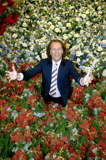 (dpa) - Dutch star violinist Andre Rieu smiles while standing in a sea of artificial flowers in Maastricht, the Netherlands, 02 November 2005. The stage decoration has been placed ready for being packed at the warehouse next to his studio in Masstricht. The 56-year-old musician is about to start the first part of his tour through Canada and the USA, where he will perform at 13 mayor cities. The complete equipment of his crew, which numbers 40 people, was already loaded into containers and shipped at the beginning of November. Rieu will continue his Germany tour with a New Year's concert in Cologne, Germany on 01 January 2006. Photo: Achim Scheidemann