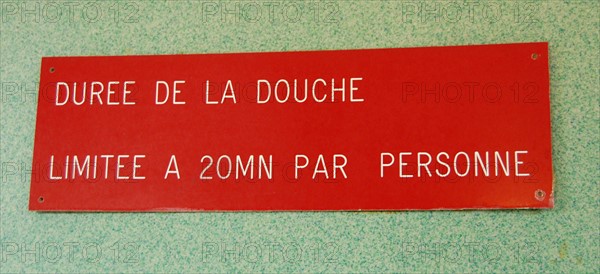 Ein Hinweisschild mit der Aufschrift: "Duree de la douche limitee a 20...
