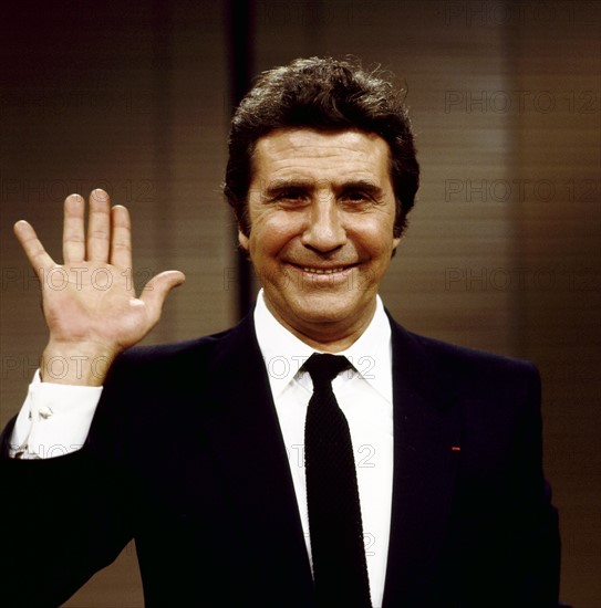 Gilbert BÉCAUD wintk in die Kamera