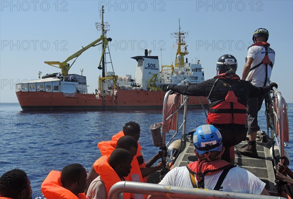 Von einem Schlauchboot gerettete Migranten werden am 27.06.2017 auf das Rettungsschiff «Aquarius» der Hilfsorganisationen Ärzte ohne Grenzen und SOS Mediterranee gebracht.    (zu dpa "Grüne weisen Vorwürfe gegen Seenotretter im Mittelmeer zurück" vom 07.07.2017) Foto: Lena Klimkeit/dpa | Verwendung weltweit