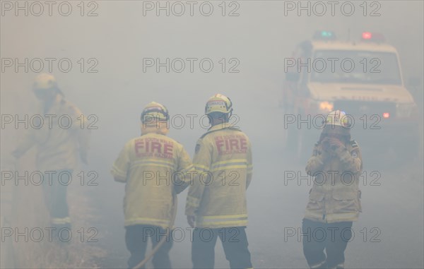 Firefighters take a break in smoke while battling bushfires near Taree, New South Wales, Australia, Nov. 11, 2019