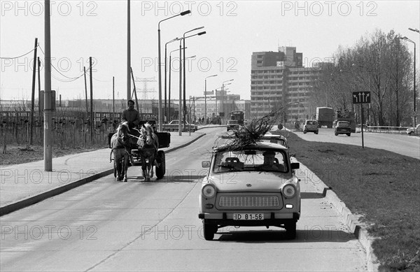Carriage and Trabant car on a barely used street near a district of prefabricated buildings east of Berlin
