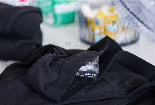 The label of period underwear symbolically depicts five drops for strong absorbency. (posed scene) Behind the underwear is a container of tampons and a pack of pads. Period underwear is increasingly conquering the market and, according to manufacturers, is intended to be an environmentally friendly alternative to disposable products. (To dpa: "Sustainable period panties? Experts warn against biocides")