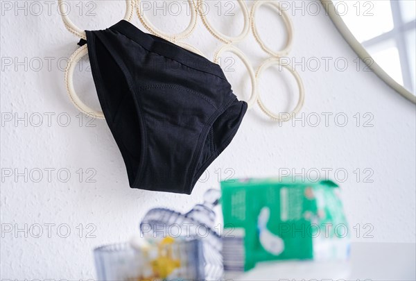 Period underwear hangs on a hanger in a room. (posed scene) Underneath are a pack of pads and a container of tampons. Period panties are increasingly conquering the market and, according to manufacturers, are supposed to be an environmentally friendly alternative to disposable products. (To dpa: "Sustainable period panties? Experts warn against biocides")