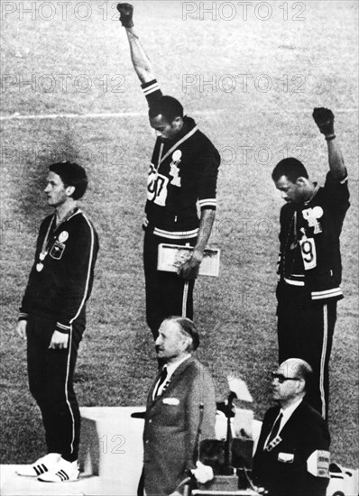 Die US-amerikanischen Läufer Tommie Smith und John Carlos, die bei den Olympischen Sommerspielen in Mexiko über 200 Meter Gold und Bronze erkämpft hatten, nutzten die Siegerehrung am Abend des 16.10.1968, um mit geballter Faus für die Farbigenbewegung "Black Power" zu demonstrieren. Links der Silbermedaillengewinner Peter Norman aus Australien.