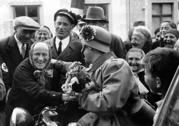 The Nazi propaganda picture shows the reception of German troops by Sudeten men and women in Egerland, Sudetenland (Czech Republic) in October 1938. The original text from the Nazi news report on the back of the picture reads: "Moving rally of joy in Egerland. An almost indescribable receptions was prepared for German troops, who were ordered to liberate the Sudetenland by the Fuhrer, by the Sudeten Germans as they marched in peacefully. Our picture shows an old Sudeten German woman from Bergdorf joyously handing a flower to the arriving German troops." Photo: Fotoarchiv für Zeitgeschichte/Archive - NO WIRE SERVICE || Mininum fee EUR 40