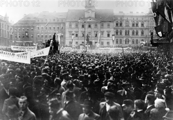 Das Motiv aus der nationalsozialistischen Propaganda zeigt die Maikundgebung am 01.05.1938 in Teplitz-Schönau (heute Teplice in Tschechien), auf der Konrad Henlein, Führer der Sudetendeutschen Partei (SdP), eine Rede hält. Der Originaltext der nationalsozialistischen Berichterstattung auf der Rückseite des Bildes lautet: "Die Sudetendeutschen feiern den 1. Mai. Die gewaltige Kundgebung der Sudetendeutschen in Teplitz-Schönau. Der bis auf den letzten Platz gefüllte Marktplatz in Teplitz-Schönau, während der eindrucksvollsten Maifeier, auf welcher Konrad Henlein sprach." Foto: Fotoarchiv für Zeitgeschichte/Archiv - KEINE BILDFUNKVERWENDUNG - || Mininum fee EUR 40