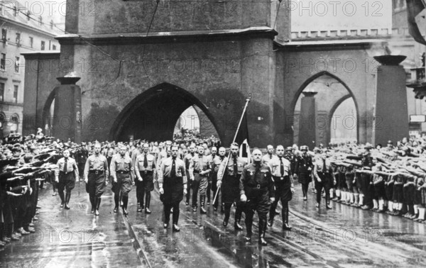 Beim Erinnerungsmarsch 1938 an den Putsch vom 9. November 1923 marschiert Adolf Hitler mit den alten Kämpfern der NSDAP vom Bürgerbräukeller zur Feldherrnhalle in der Innenstadt Münchens. Hier passiert die Kolonne das Isartor, allen voran Gauleiter Julius Streicher, gefolgt von der "Blutfahne", 9. November 1938.