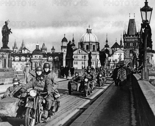 Die deutsche Wehrmacht marschiert in Prag ein. Die bewaffneten Soldaten fahren mit Motorrädern über die Karlsbrücke. Sechs Monate nach dem Münchener Abkommen besetzt Hitler die restlichen Gebiete Böhmen und Mährens und auf seinen Druck gründet sich die Erste Slowakische Republik. (Aufnahmedatum: 01.03.1939-31.03.1939)