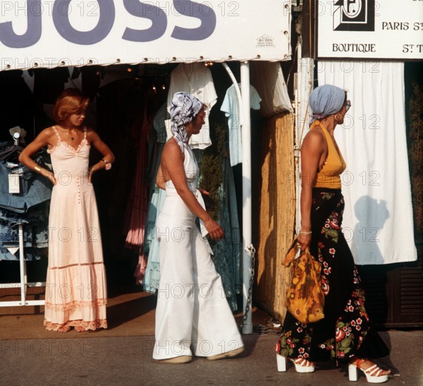 Where the rich and beautiful go on holiday: Fashion-conscious tourists with headscarves and platform soles on their afternoon stroll through the southern French seaside resort of St. Tropez. Taken in 1975.