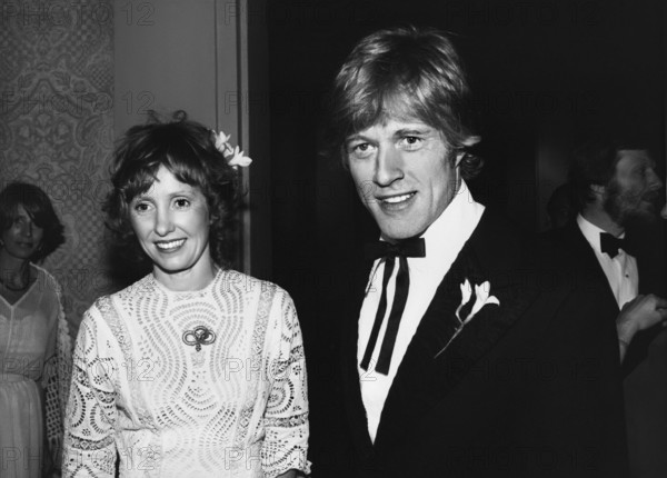 Lola und Robert Redford (Mitte der 1970er Jahre) / Personen, Ehepaar, married, verheiratet, Frau Spitzenkleid, Haarschmuck, Mann Blume am Revers