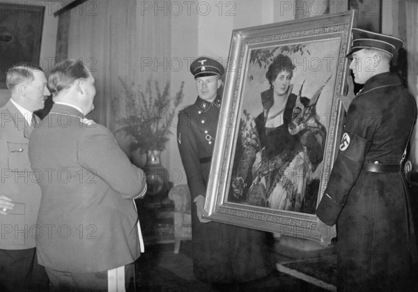 Adolf Hitler presents to Hermann Goring a painting that two SS men hold.