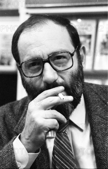 Umberto Eco (Schriftsteller) 10/83 ru Umberto Eco bei der Frankfurter Buchmesse im Oktober 1983 Mann Italien Italiener Autor Schriftstellerei Literatur Medien Medienwissenschaftler Semiotiker Semiotik Postmoderne Romane Epik "Der Name der Rose" dunkelhaarig kurzhaarig Bart bärtig Vollbart Brille Brillenträger seriös Anzug Hemd Jackett Krawatte sitzen sitzend Zigarette halten halten in der Hand rauchen rauchend Messe Buch Bücher Frankfurt Regale Bücherregale Ausstellung Hochformat hoch Portrait halb sw