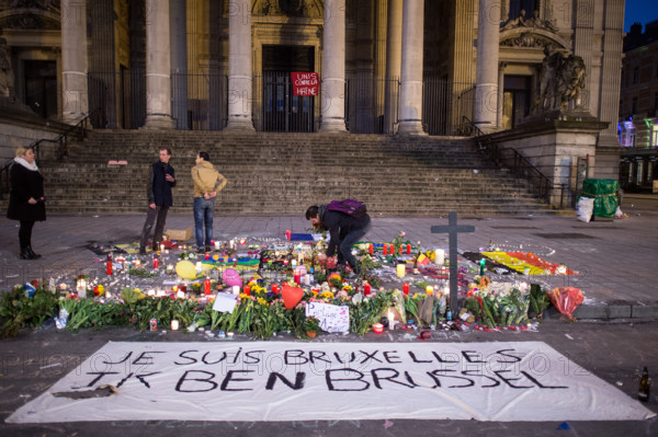 A man lights a candle behind a banner that reads 'Je suis Bruxelles Ik ben Brussel' (lit. I am Brussels) in front of the stock exchange at Place de la Bourse in Brussels, Belgium, 23 March 2016. At least 30 people have been killed and more than 180 were injured in a new series of terror attacks that rocked Brussels, Belgium on 22 March 2016. Photo: FEDERICO GAMBARINI/dpa