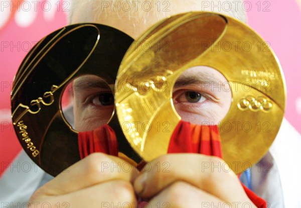 (dpa) - German Andre Lange looks through his two gold medals at the Olympic bobsleigh and toboggan run in Cesana Pariol, Italy, 25 February 2006. Lange won gold in the two-man as well as in the four-man bobsleigh. Photo: Arne Dedert