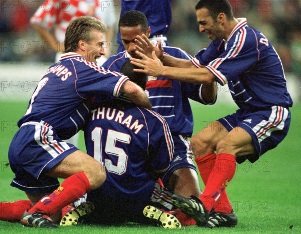French team captain Didier Deschamps (L), forward Thierry Henry (C, back) and midfielder Youri Djorkaeff (R) gather around goal scorer Lilian Thuram (15) in order to embrace and congratulate him after Thuram scored the winning goal during the 1998 World Cup semifinal France against Croatia at Saint Denis' Stade de France, Paris, France, 8 July 1998. France won the game 2-1 against Croatia and qualified for the World Cup final against titleholder Brazil.