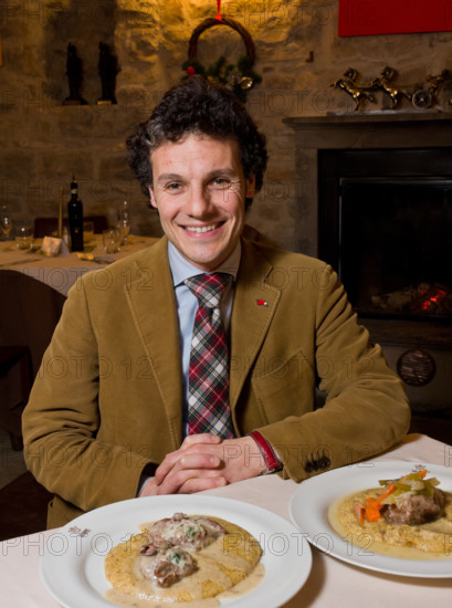 Città alta, Ristorante DAMIMMO:  Massimo Amaddeo, uno dei titolari, siede a un tavolo davanti a due piatti della cucina bergamasca (guancialino stufato con lesso di verdure e polenta, e oseli scapacc alle erbette e Branzi d'alpeggio).
Bergamo (BG), Lombardia, Italia - Italy