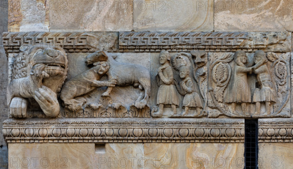 Fidenza, duomo (Cathedral of San Donnino), right tower (Trabucco Tower), west front: detail of the frieze with “Stories of Berta, Milone and Rolandino” told by two Chanson de Geste between the end of the 12th and the beginning of the 13th century.
From the left, a young lion – an allegory of Rolandino – bites a horse in the neck. Milone, followed by his son Rolandino, goes into the woods to get wood to sell. Milone fights with a bandit who wants to kidnap Berta, who has become pregnant.
Work by Benedetto Antelami e workshop.
Cattedrale di San Donnino, Fidenza (PR), Emilia-Romagna, Italia - Italy