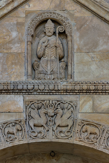 Fidenza, Duomo (Cattedrale di San Donnino), facciata, timpano del portale destro: “figura di Vescovo”. il personaggio è seduto su un faldistorio, vestito di camice, cotta e casula, con mitria e pastorale. Tradizionalmente nella figura è stato riconosciuto l’Arciprete della chiesa di S. Donnino, ma il pallio riservato sin dal medioevo agli arcivescovi metropoliti e ai primati, fa dubitare di questa interpretazione. Opera di Benedetto Antelami e bottega.

[ENG]
Fidenza, Duomo (St. Donnino Cathedral), the facade, tympanum of the right portal: “figure of a Bishop”. The figure is seated on a faldstool, dressed in a cassock, surplice and chasuble, with a mitre and pastoral staff. Traditionally, the figure has been identified as the Archpriest of the church of S. Donnino, but the pallium reserved since the Middle Ages for metropolitan archbishops and primates casts doubt on this interpretation. Work by Benedetto Antelami and workshop.
Cattedrale di San Donnino, Fidenza (PR), Emilia-Romagn...