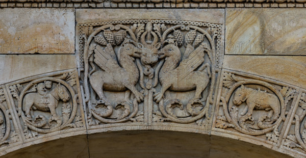 Fidenza, Duomo (Cattedrale di San Donnino), portale destro: dettaglio dell’arco del protiro.
Particolare di due creature fantastiche con una maschera cornuta dal cui ghigno esce un serpente, chiaro riferimento a Satana.
Opera di Benedetto Antelami e bottega.

[ENG]
Fidenza, Duomo (Cathedral of San Donnino), right portal: detail of the arch of the porch.
In the centre, at the top: two fantastic creatures with a horned mask from whose grin a snake emerges, a clear reference to Satan.
Work by Benedetto Antelami e workshop.
Cattedrale di San Donnino, Fidenza (PR), Emilia-Romagna, Italia - Italy