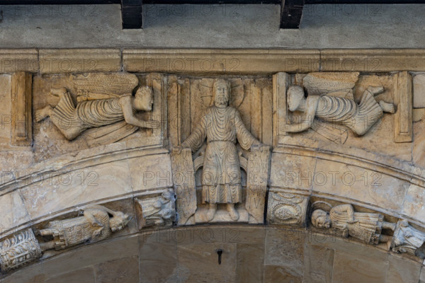 Fidenza, duomo (Cattedrale di San Donnino), facciata, portale maggiore: dettaglio dell’archivolto con “Cristo assiso”. La figura è seduta su un  su un bisellio e tiene nelle mani due cartigli svolti con iscrizioni richiamanti la Vecchia e la Nuova Legge: (sn) AV/DI – ISR[AE]L / MAN/DA/TA – VI/TA = Ascolta Israele i comandamenti della vita (Bar 3, 9); (ds) BEATI / PAVPE/RES / SPIRI/TV  = Beati i poveri di spirito (Mt 5, 3).
In basso due delle figure raffiguranti “I comandamenti” e “Le Beatitudini”.
Opera di Benedetto Antelami e bottega.

[ENG]
Fidenza, duomo (Cathedral of San Donnino), facade, main portal: detail of the archivolt with “Christ seated”. The figure is seated on a chamfer and holds in his hands two scrolls with inscriptions recalling the Old and New Law: (sn) AV/DI – ISR[AE]L / MAN/DA/TA – VI/TA = Listen, Israel, to the commandments of life (Bar 3, 9); (ds) BEATI / PAVPE/RES / SPIRI/TV = Blessed are the poor in spirit (Mt 5, 3).
Below, two of the figures depicting “Th...