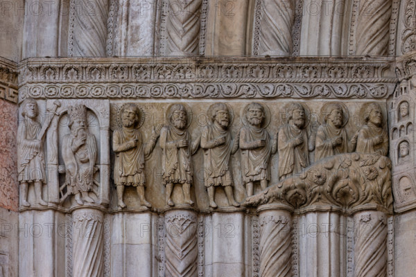 Fidenza, duomo (Cattedrale di San Donnino), facciata, portale maggiore: dettaglio dell’archivolto con “Storie di San Donnino”.
L'imperatore Massimiano si accarezza la barba (meditando la vendetta). Il santo fugge assieme ai suoi compagni (Donnino è il primo da sinistra, con l'aureola abbellita da un cerchio di piccoli fori).
Opera di  Benedetto Antelami e bottega.

[ENG]
Fidenza, duomo (Cathedral of San Donnino), facade, main portal: detail of the archivolt with “Stories of St. Donnino”. Emperor Maximian strokes his beard (meditating revenge).
The saint flees with his companions (Donnino is the first from the left, with his halo embellished with a circle of small holes).
Work by Benedetto Antelami and workshop.
Cattedrale di San Donnino, Fidenza (PR), Emilia-Romagna, Italia - Italy