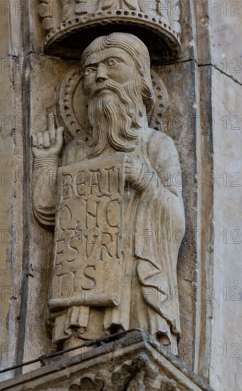 Fidenza, Duomo (Cattedrale di San Donnino), facciata, portale maggiore: dettaglio dell’archivolto con “Allegorie delle Beatitudini”. Apostolo con l’iscrizione:   BEATI / Q[VI] N[VN]C / ESVRI/TIS = Beati quelli che hanno fame (Lc 6, 21). 
Opera di Benedetto Antelami e bottega.

[ENG]
Fidenza, Duomo (Cathedral of San Donnino), facade, main portal: detail of the archivolt with “Allegories of the Beatitudes”. An apostle with the inscription:   BEATI / Q[VI] N[VN]C / ESVRI/TIS = Blessed are those who hunger (Lc 6, 21). 
Work by Benedetto Antelami and workshop.
Cattedrale di San Donnino, Fidenza (PR), Emilia-Romagna, Italia - Italy