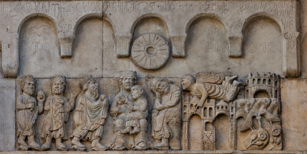 Fidenza, duomo (Cattedrale di San Donnino), sculture tra il portale maggiore e quello di sinistra: “Adorazione dei Magi e sogno di Giuseppe”. Opera di Benedetto Antelami e bottega.
A sinistra si vedono i tre Re Magi che rendono omaggio al Bambino benedicente seduto sulle ginocchia della Madre in maestà; al fianco della Madonna, S. Giuseppe, seduto di profilo, che dorme.
A destra, in un paesaggio caratterizzato dalla presenza di edifici, un angelo raggiunge in volo Giuseppe per parlargli in sogno. All’estrema destra, nella parte inferiore, due colombe in un giardino bevono da una fonte posate su zolle fiorite che raffigurano la terra d’Egitto.
Sui due pannelli in arenaria posti sopra gli altri due, è scolpita una cornice con cinque archetti pensili e sotto quello centrale – sulle teste della Madonna e di Giuseppe – un disco a forma di macina da mulino simboleggia la stella che indicò la via ai Re Magi.
Sugli archetti sono incise a lettere capitali le iscrizioni seguenti: CASPAR . BA...