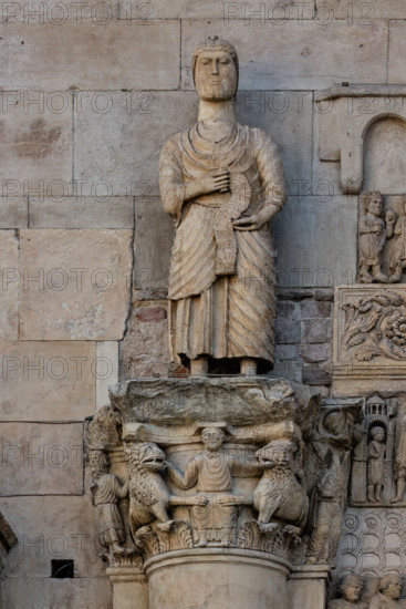 Fidenza, cathedral (Cathedral of San Donnino), sculptures between the main portal and the left one:
Detail of “Saint Simon the Apostle showing the way to Rome to pilgrims”; the statue holds in his hands a phylactery that unfolds downwards on which the inscription is engraved in capital letters: S.IMO / APLS / EUDI / ROMA / SCDS / MON / A[…]RAT / HAC / VIAM (Simon Apostolus eundi Romam demonstrat hanc viam).
The statue surmounts the capital with “Daniel in the lions’ den”.
Work by Benedetto Antelami and workshop.
Cattedrale di San Donnino, Fidenza (PR), Emilia-Romagna, Italia - Italy