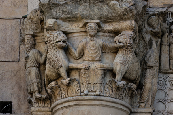 Fidenza, cathedral (Cathedral of San Donnino), sculptures between the main portal and the left one:
Detail of the capital with “Daniel in the lions’ den”. The figurative semi-capital that depicts on the front the biblical scene – of Christological symbolism – of the prophet Daniel who, thrown into the den, is surrounded by tamed lions. On the right side of the semi-capital is depicted the prophet Habakkuk with food for Daniel and on the left side the angel who brought him (Dn 14,33-38). On the abacus of the semi-capital is engraved in capital letters the inscription: […]C DANIEL IVSTUS INLA EST CV LEONV[M] ([Abacu]c . Daniel iustus in lacu est cum leonum).
Work by Benedetto Antelami and workshop.
Cattedrale di San Donnino, Fidenza (PR), Emilia-Romagna, Italia - Italy