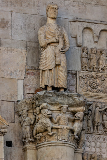 Fidenza, duomo (Cattedrale di San Donnino), sculture tra il portale maggiore e quello di sinistra: 
il capitello con “Daniele nella fossa dei leoni”, sormontato dalla statua con “San Simone Apostolo che mostra la via di Roma ai pellegrini”;
Cattedrale di San Donnino, Fidenza (PR), Emilia-Romagna, Italia - Italy