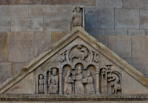 Fidenza, duomo (Cattedrale di San Donnino), portale sinistro, timpano. Nel frontone si leggono, da sinistra, tre scene: L'imperatore Carlo Magno, con un armigero alla sua destra;
Papa Adriano II che porge all'arciprete di San Donnino la mitria e il pastorale (simboli della dignità episcopale); il miracolo dell'ammalato guarito (miracolo compiuto da San Donnino).
Nell’acroterio sul timpano, é raffigurato un personaggio, probabilmente Oberto II Pallavicino condottiero posto da Federico II di Svevia alla guida della città dal 1249 al 1268.

Opera di Benedetto Antelami e bottega.

[ENG]
Fidenza, duomo (Cathedral of San Donnino), left portal, tympanum. In the pediment, from the left, three scenes can be read: Emperor Charlemagne, with a man-at-arms to his right;
Pope Adrian II who offers the archpriest of San Donnino the mitre and the pastoral staff (symbols of episcopal dignity); the miracle of the healed sick man (miracle performed by San Donnino).
In the acroterion on the tympan...