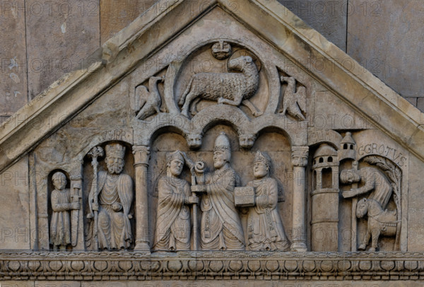 Fidenza, duomo (Cattedrale di San Donnino), portale sinistro, timpano. Nel frontone si leggono, da sinistra, tre scene: L'imperatore Carlo Magno, con un armigero alla sua destra;
Papa Adriano II che porge all'arciprete di San Donnino la mitria e il pastorale (simboli della dignità episcopale); il miracolo dell'ammalato guarito (miracolo compiuto da San Donnino).
Nell’acroterio sul timpano, é raffigurato un personaggio, probabilmente Oberto II Pallavicino condottiero posto da Federico II di Svevia alla guida della città dal 1249 al 1268.

Opera di Benedetto Antelami e bottega.

[ENG]
Fidenza, duomo (Cathedral of San Donnino), left portal, tympanum. In the pediment, from the left, three scenes can be read: Emperor Charlemagne, with a man-at-arms to his right;
Pope Adrian II who offers the archpriest of San Donnino the mitre and the pastoral staff (symbols of episcopal dignity); the miracle of the healed sick man (miracle performed by San Donnino).
In the acroterion on the tympan...