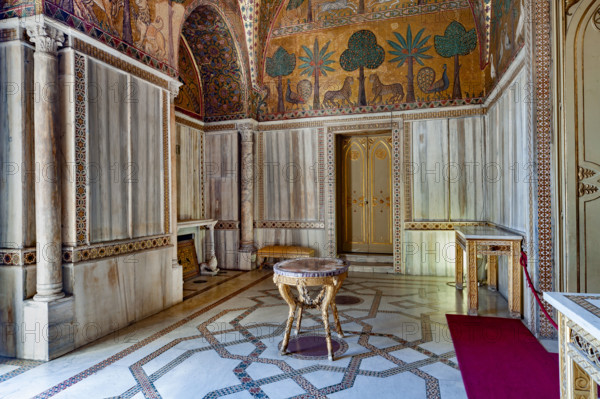 Palermo, Palazzo Reale o Palazzo dei Normanni, Torre Pisana, Sala di Re Ruggero: veduta della sala voluta da Re Ruggero II d'Altavilla. E' caratterizzata da ampie superfici a mosaico di grande pregio raffiguranti elementi vegetali (palme e banani) e scene di carattere aulico e venatorio, simboli del potere normanno (battute di caccia con arcieri e cervi, rappresentati pavoni, cigni, oltre i mitologici centauri, grifi e altri animali esotici tra cui leopardi e tigri fra lussureggiante vegetazione). I mosaici sono di stile greco - bizantino (secolo XIII).

[ENG]
Palermo, The Royal Palace or Palazzo dei Normanni (Palace of the Normans), Pisana Tower,  the King Roger Room: view of the Room which was commissioned by King Roger II d'Altavilla. It is characterized by large mosaic surfaces of great value representing plant elements (palms and banana trees) and scenes of courtly and hunting style, symbols of the Norman power (hunting scenes with archers and deer, peacocks, swans, and mytholo...