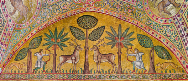 Palermo, Palazzo Reale o Palazzo dei Normanni, Torre Pisana, Sala di Re Ruggero: mosaici della sala voluta da Re Ruggero II d'Altavilla. E' caratterizzata da ampie superfici a mosaico di grande pregio raffiguranti elementi vegetali e scene di carattere aulico e venatorio, simboli del potere normanno (battute di caccia con arcieri e cervi, rappresentati pavoni, cigni, oltre i mitologici centauri, grifi e altri animali esotici  fra lussureggiante vegetazione). I mosaici sono di stile greco - bizantino (secolo XIII).
Particolare con arcieri, cervi, cani  e alberi (banani e palme).

[ENG]
Palermo, The Royal Palace or Palazzo dei Normanni (Palace of the Normans), Pisana Tower,  the King Roger Room: view of the Room which was commissioned by King Roger II d'Altavilla. It is characterized by large mosaic surfaces of great value representing plant elements  and scenes of courtly and hunting style, symbols of the Norman power (hunting scenes with archers and deer, peacocks, swans, and mytho...