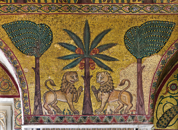 Palermo, Palazzo Reale o Palazzo dei Normanni, Torre Pisana, Sala di Re Ruggero: mosaici della sala voluta da Re Ruggero II d'Altavilla. E' caratterizzata da ampie superfici a mosaico di grande pregio raffiguranti elementi vegetali e scene di carattere aulico e venatorio, simboli del potere normanno (battute di caccia con arcieri e cervi, rappresentati pavoni, cigni, oltre i mitologici centauri, grifi e altri animali esotici  fra lussureggiante vegetazione). I mosaici sono di stile greco - bizantino (secolo XIII).
Particolare con leoni e alberi (banani e palme).

[ENG]
Palermo, The Royal Palace or Palazzo dei Normanni (Palace of the Normans), Pisana Tower,  the King Roger Room: view of the Room which was commissioned by King Roger II d'Altavilla. It is characterized by large mosaic surfaces of great value representing plant elements  and scenes of courtly and hunting style, symbols of the Norman power (hunting scenes with archers and deer, peacocks, swans, and mythological centaurs...