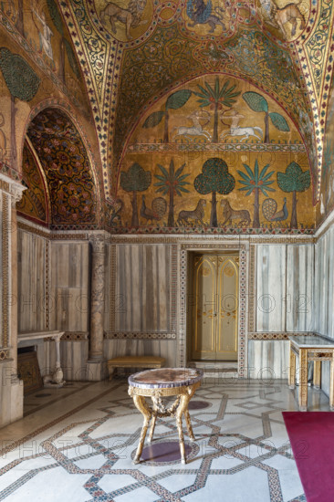 Palermo, Palazzo Reale o Palazzo dei Normanni, Torre Pisana, Sala di Re Ruggero: veduta della sala voluta da Re Ruggero II d'Altavilla. E' caratterizzata da ampie superfici a mosaico di grande pregio raffiguranti elementi vegetali (palme e banani) e scene di carattere aulico e venatorio, simboli del potere normanno (battute di caccia con arcieri e cervi, rappresentati pavoni, cigni, oltre i mitologici centauri, grifi e altri animali esotici tra cui leopardi e tigri fra lussureggiante vegetazione). I mosaici sono di stile greco - bizantino (secolo XIII).

[ENG]
Palermo, The Royal Palace or Palazzo dei Normanni (Palace of the Normans), Pisana Tower,  the King Roger Room: view of the Room which was commissioned by King Roger II d'Altavilla. It is characterized by large mosaic surfaces of great value representing plant elements (palms and banana trees) and scenes of courtly and hunting style, symbols of the Norman power (hunting scenes with archers and deer, peacocks, swans, and mytholo...