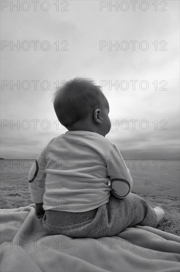 Baby Boy Sitting on Beach, Rear View