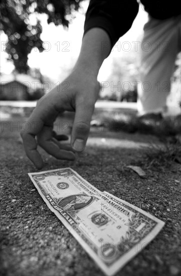 Man Picking Up Dollar Bill From Ground