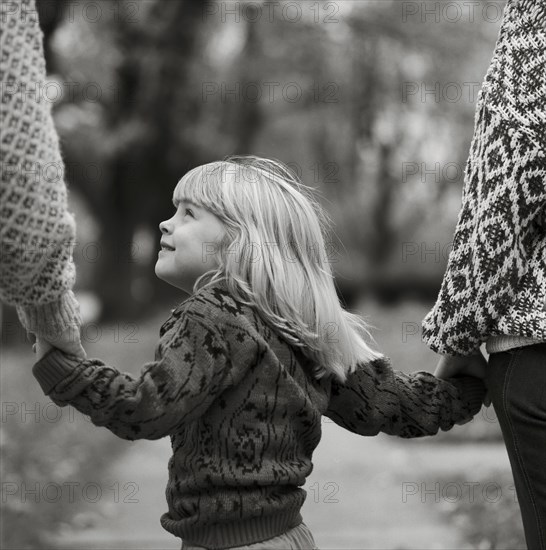 Young Blonde Girl Holding Parents' Hands