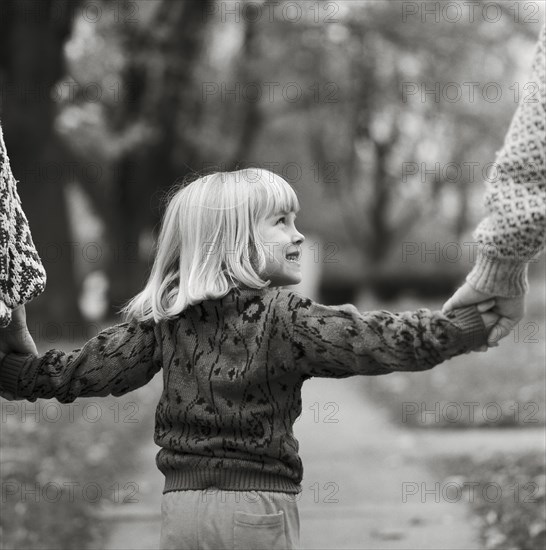 Young Blonde Girl Holding Parents' Hands