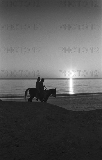 Couple Riding Horse on Beach