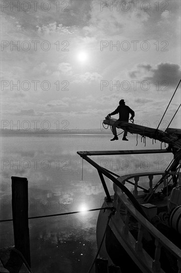 Sailor Sitting on Pole on Sailboat